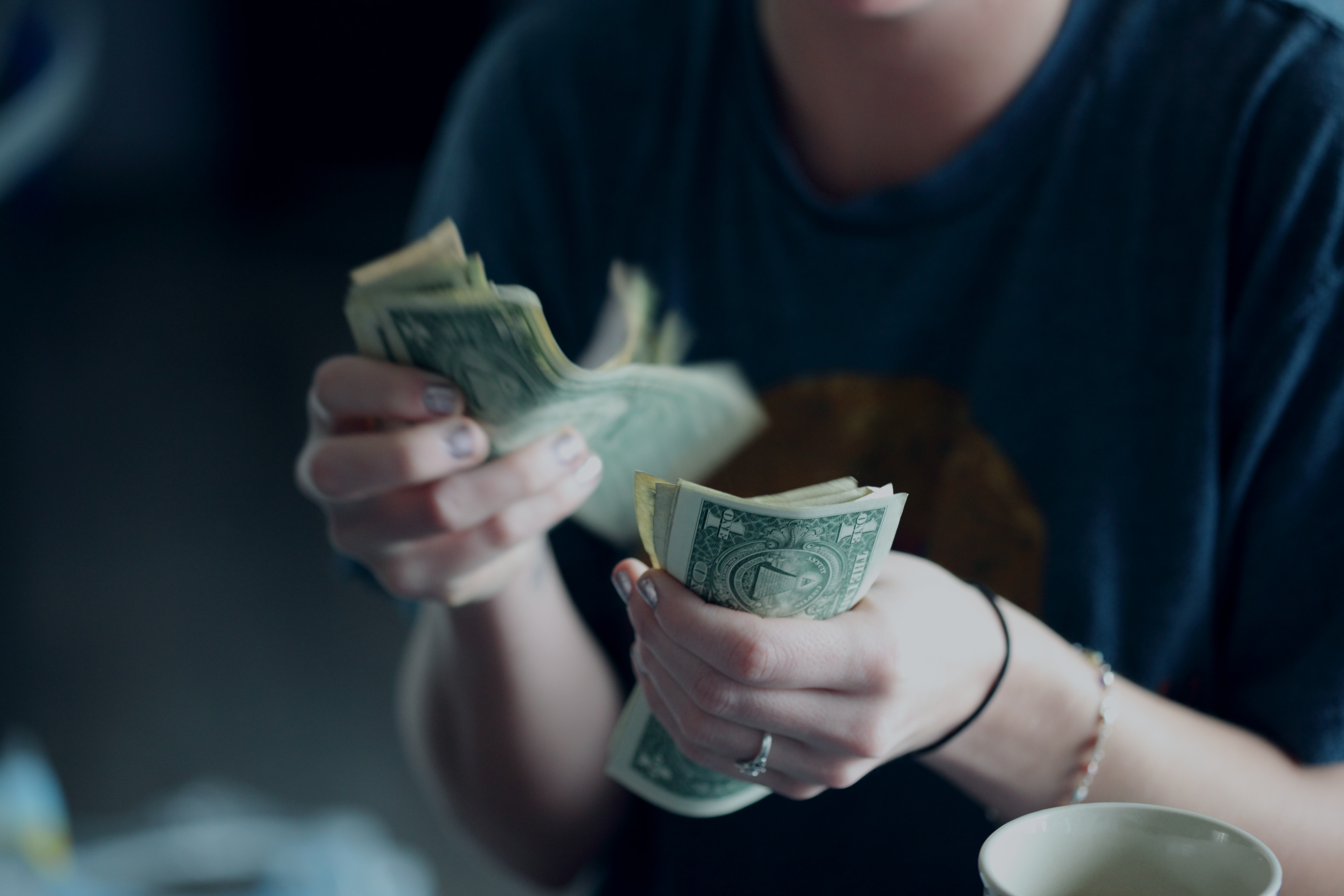 Hands counting several dollar bills. How to Engage Board Members In Fundraising