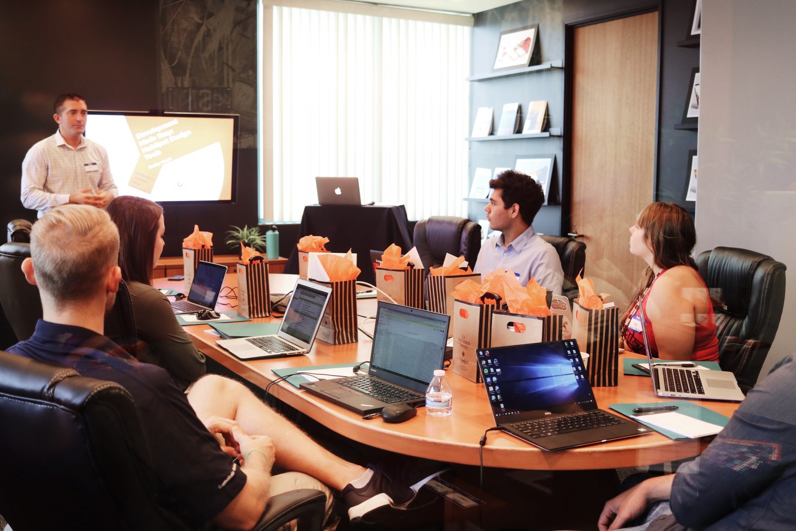 A man pitching a presentation to a conference room. Corporate sponsorships for nonprofits typically require a pitch meeting.