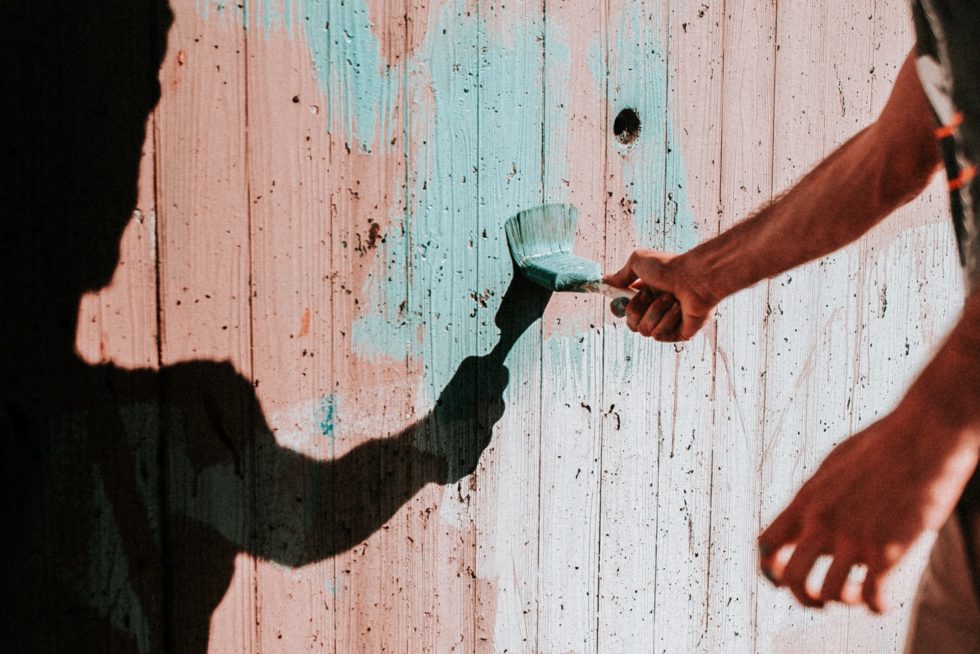 A close up of a volunteer painting a house.