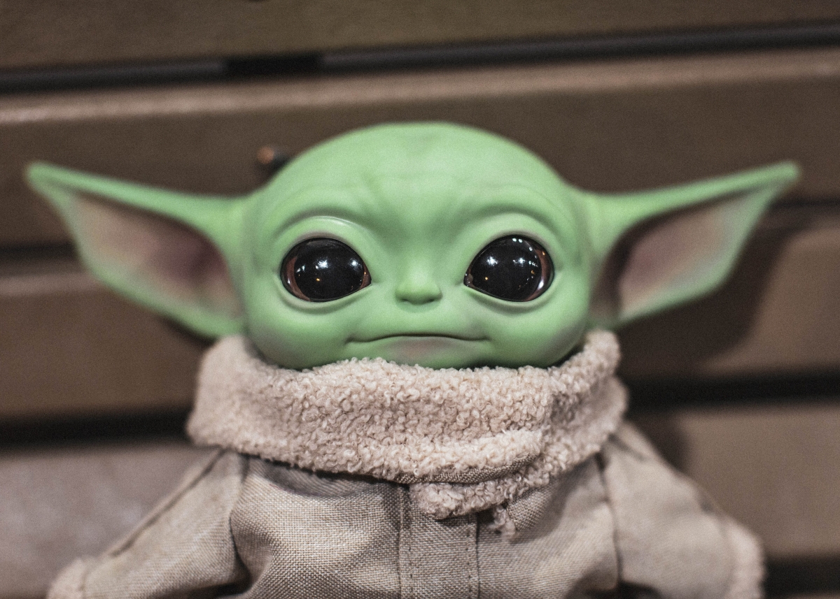 A lifelike doll of Baby Yoda looks into the camera with a serene expression