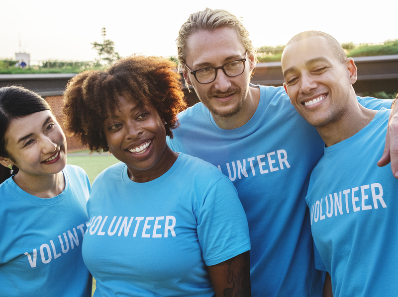 group of young adults wearing blue t-shirts printed with the word volunteer