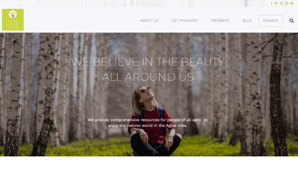 The homepage for a nature conservation nonprofit featuring the image of a woman sitting cross-legged in the woods and staring up happily at the trees above her. 