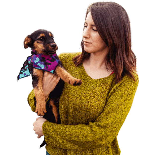 A woman holds a puppy that has a scarf around its neck