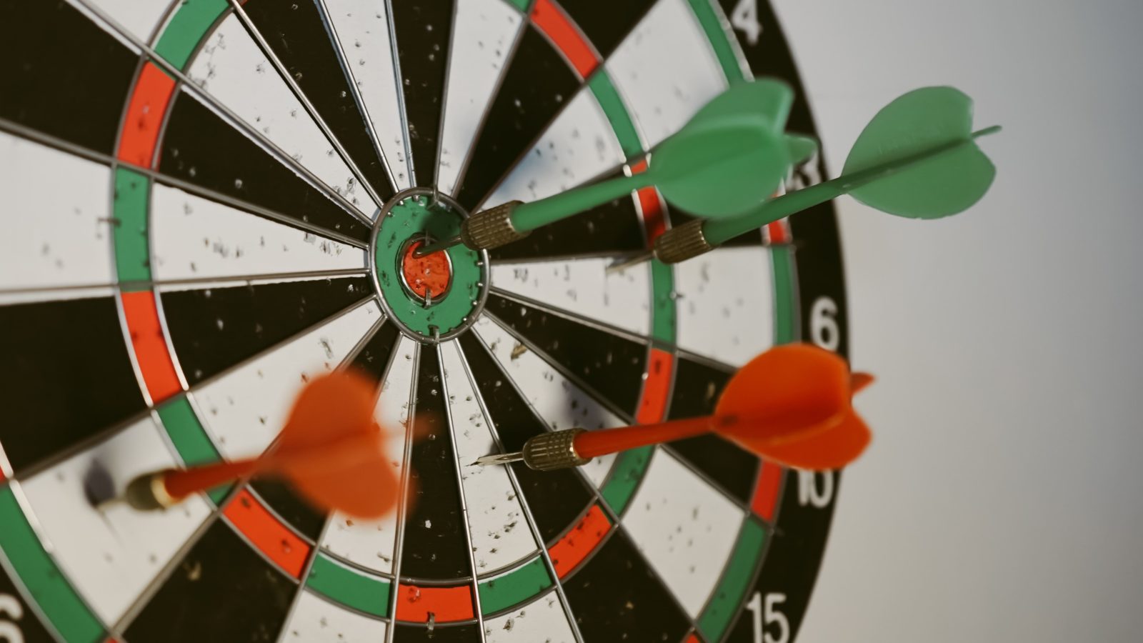 a dart board with 4 darts stick into it, one of them is a bullseye