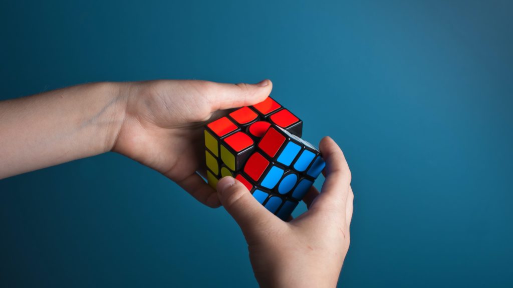 two hands holding a nearly finished rubiks cube