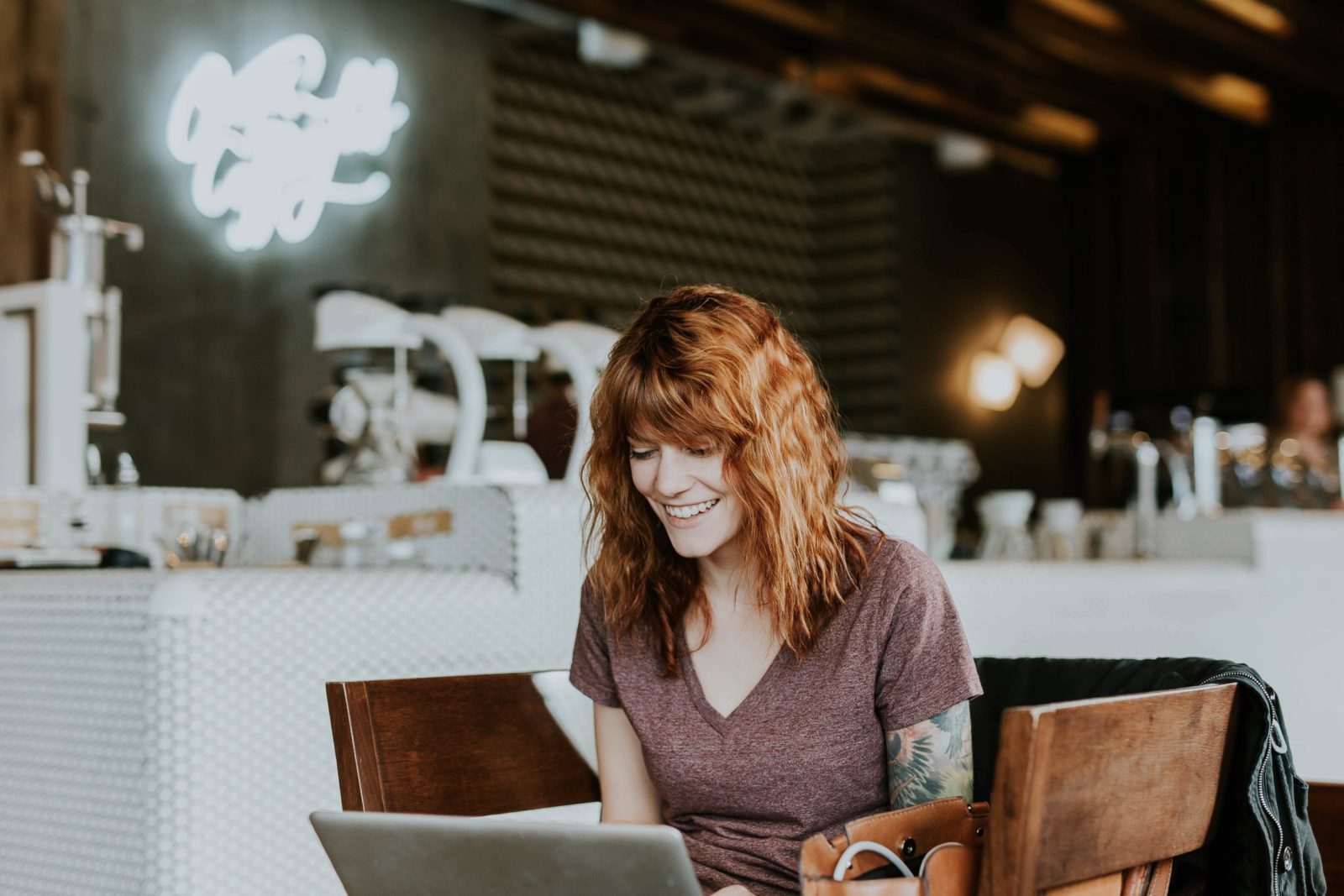 A woman with red wavy hair is sitting in a nice coffee shop. She's smiling down at her laptop, which we're positive means she's thinking about her own favorite Generosity Xchange takeaways.