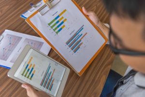 Photo taken from above a person who is looking at various graphs and data comparing them
