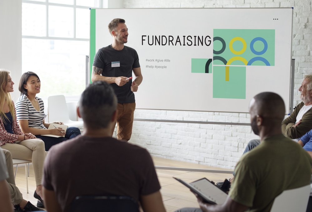 A man stands in front of a whiteboard doing a presentation on integrated fundraising tools for nonprofits.