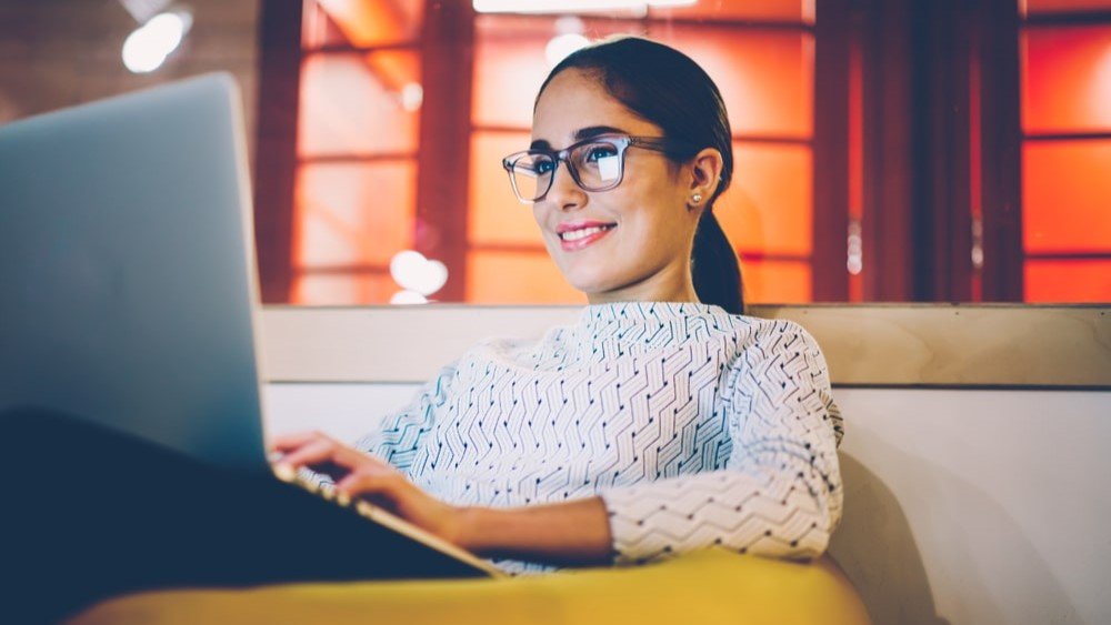 You can repurpose many of the content ideas in your nonprofits blog into other types of engaging posts. In this image, a woman with glasses sits with a laptop in front of her.