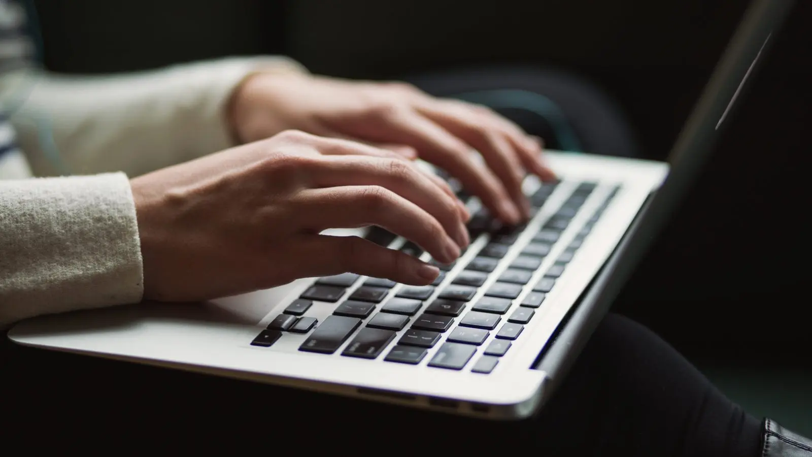 A person's hands typing on a laptop keyboard composing a GivingTuesday email.