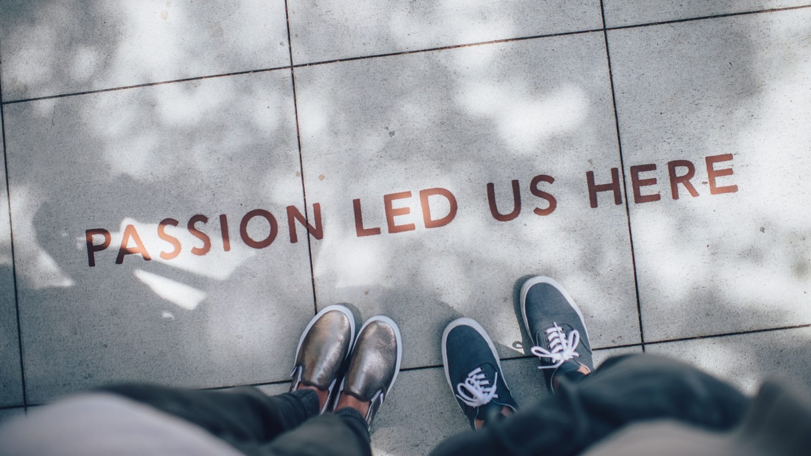 two people's shoes standing on the sidewalk next to the phrase "passion led us here"