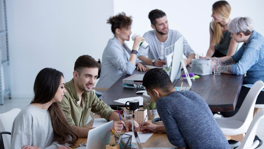 Nonprofit public relations strategies built on trust and credibility can guide your organization during difficult times. In this image, a group of individuals work at laptops on a conference table.