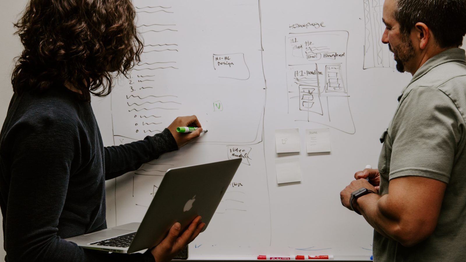 a man and woman standing in front of a white board, mapping out their donor data migration plan