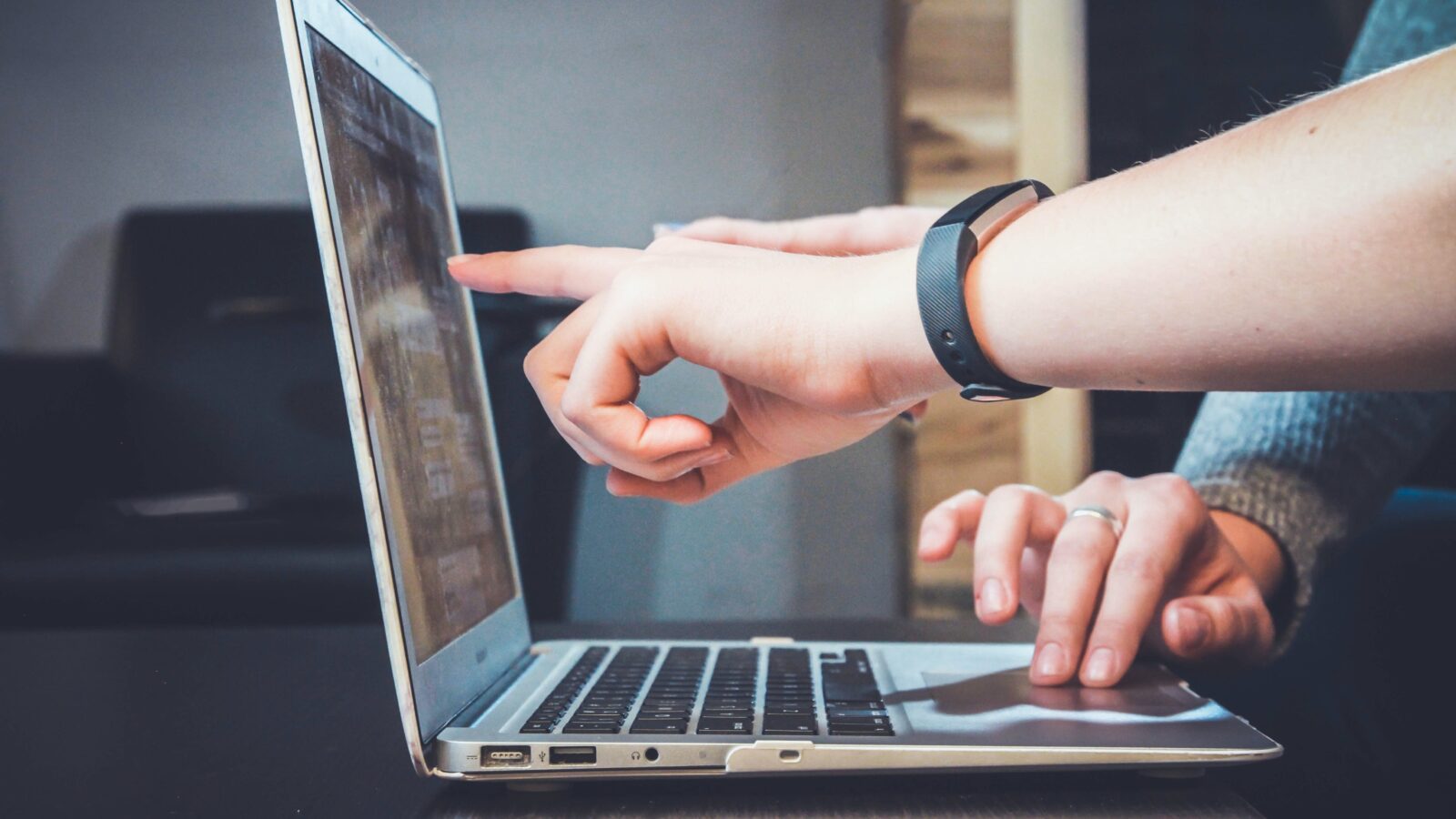 A solid nonprofit change management strategy will help your staff members quickly adopt new technologies. In this image, a person's arm points out something on the screen of another person's MacBook laptop.