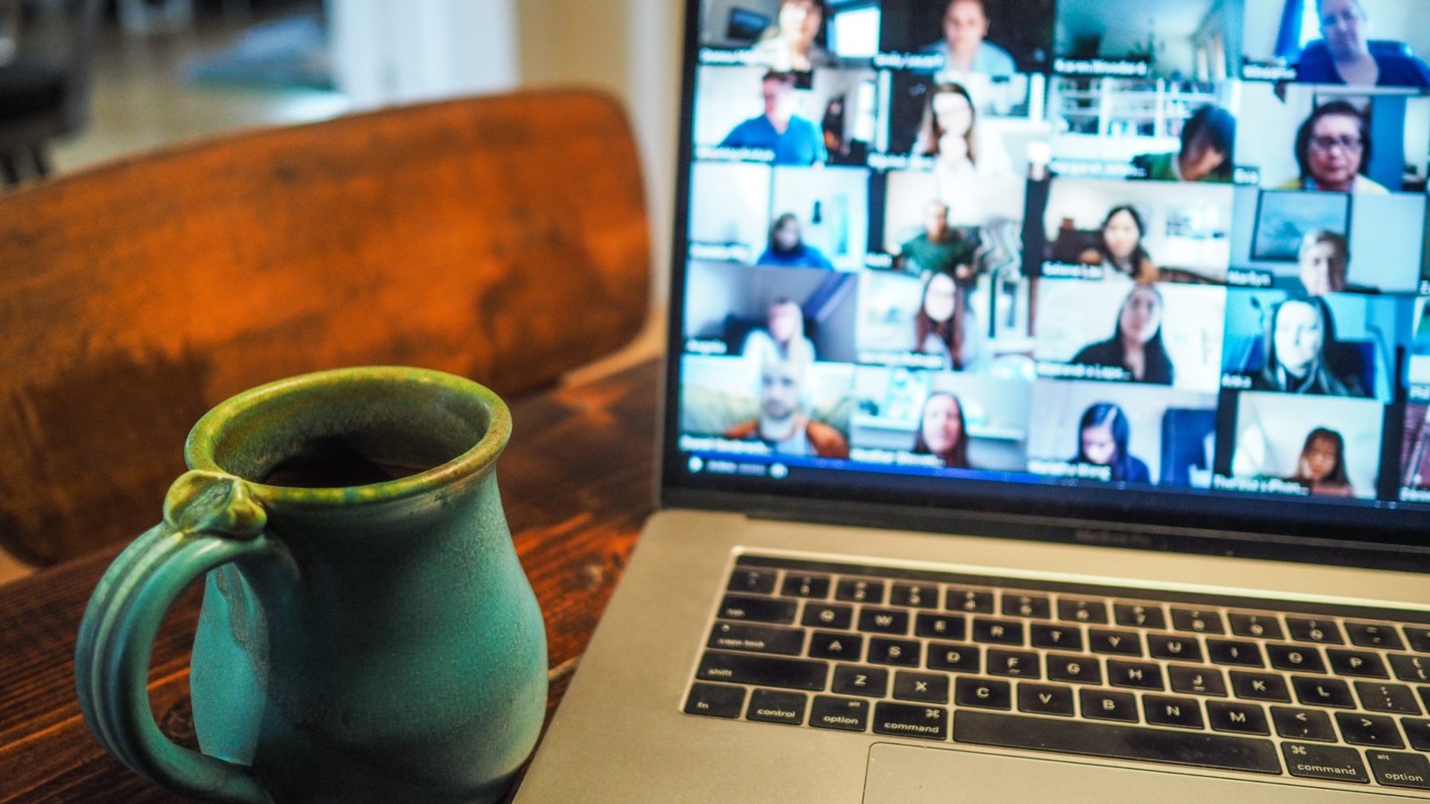 Livestreams with program leaders or beneficiaries can be good online fundraising ideas for nonprofits to engage donors. In this image, a coffee mug sits next to an open laptop that's displaying an online meeting with the different participants each appear in their own tile.