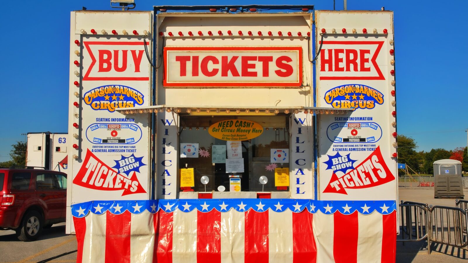 a brightly colored fair booth in the colors of the American flag with big signs that say "Buy Tickets Here"