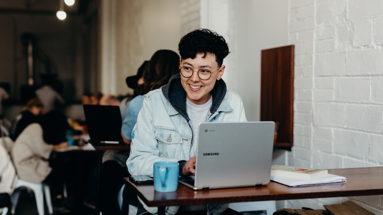 A woman using her laptop in a cafe to make a donation to her favorite nonprofit and smiling.