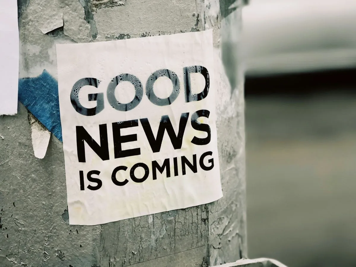 A printed out sign taped to a street light post that reads "Good News is Coming"