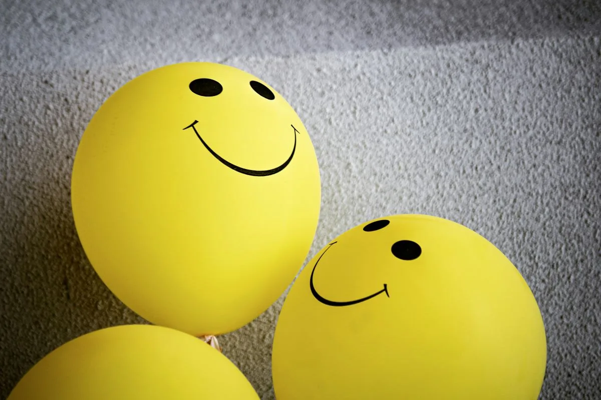two yellow balloons with happy faces on them